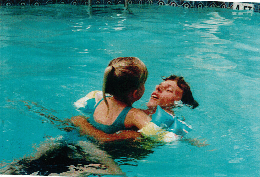 Young Felecia swimming with her father, capturing a joyful father-daughter moment from childhood.